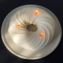 A luxurious 3-wick candle called, Serene, on a concrete Ripple tray. The candle is a twisted cable-wire shape and measures about 9 in in diameter, 2.5 inches in height and weighs 52 ounces. 